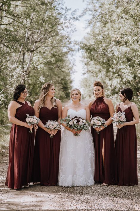 Bride with bridesmaids in burgundy dresses holding blush and burgundy bouquets with eucalytpus