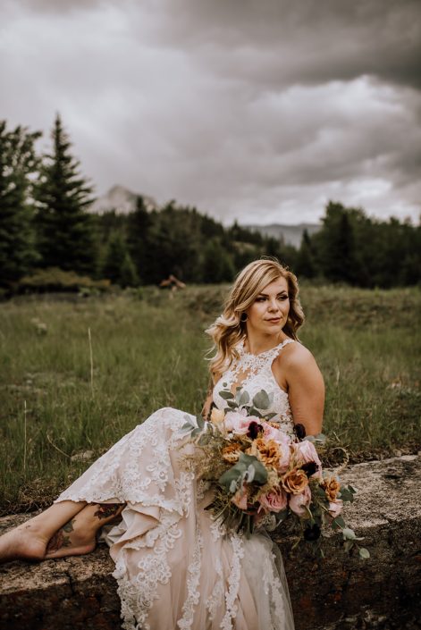 Bride in banff mountains with organic bridal bouquet of toffee roses, pink ohara garden roses, gold plumos and plum ranunculus and cinerea eucalyptus