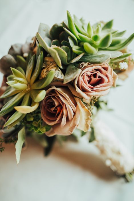 Close up photo of bride bouquet of mauve amnesia roses, paper flowers and succulents