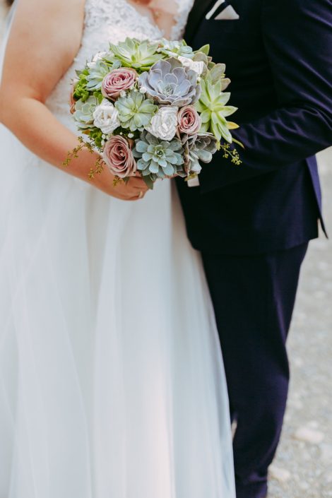 Bride bouquet f succulents and mauve amnesia roses held by bride and groom