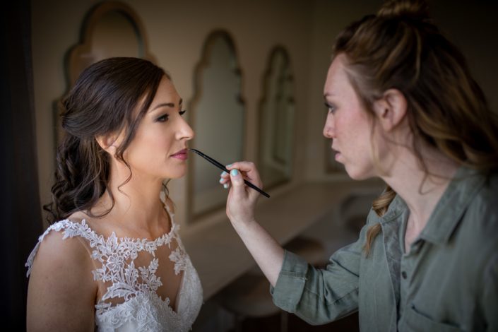 bride in white lace wedding dress with makeup artist