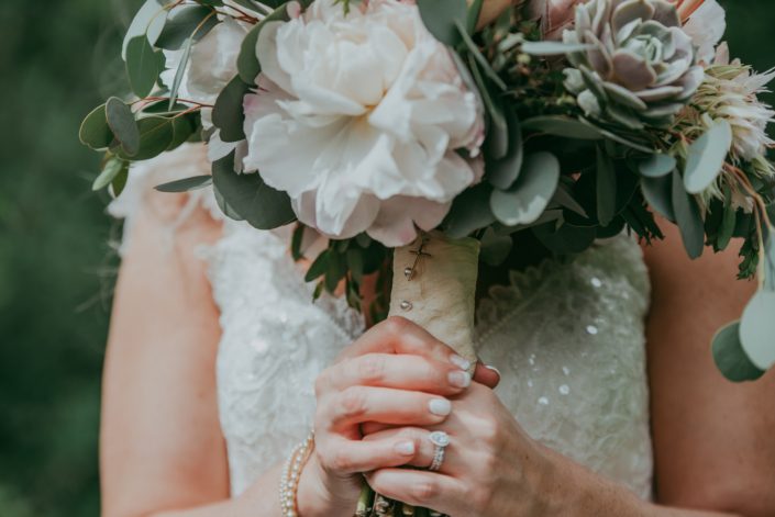 close up of bridal bouquet handle with blush penoy, lola blush succulent and silver dollar eucalyptus, handle is wrapped with ivory lace and brides rosary