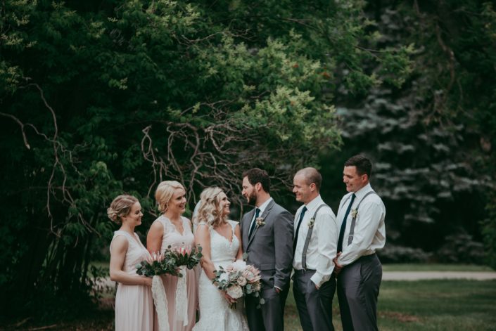 wedding party in blush and charcoal grey with bouquets of pale pink king protea and eucalyptus groomsmen in white shirts and suspenders with boutonnieres