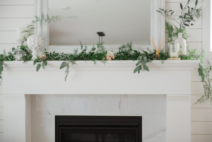 White mantle fireplace with eucalyptus, plumosa and italian ruscus greenery and accents of pale peach spray roses