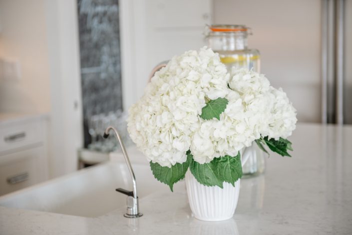 White countertop floral arrangement of white hydrangea in white ceramic vase