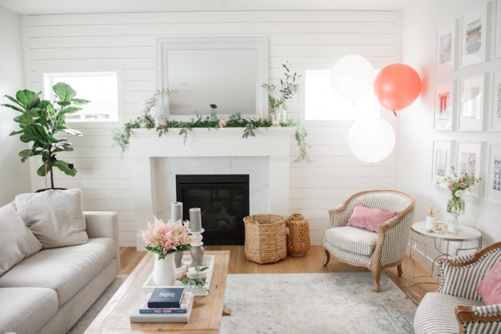bridal shower decorations including balloons, vase of pale pink astilbe, and fresh greenery along fireplace mantle
