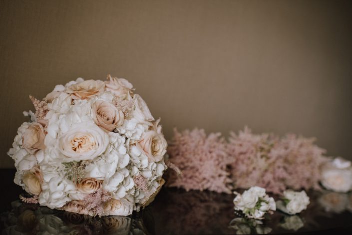 bridal bouquet designed with white hydrngea and white ohara garden roses and quicksand roses and pale pink astilbe with bridesmaids bouquets of pale pink astilbe and corsages and boutonnieres