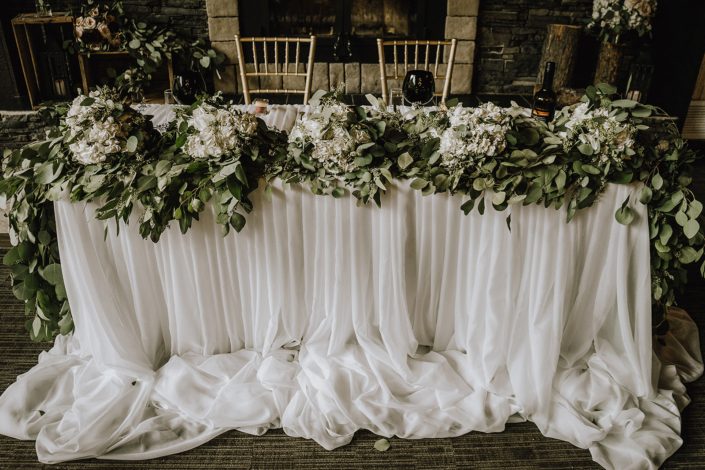 sweetheart table covered with tulle ballerina skirt linens and accented by a eucalyptus garland and white hydrangea