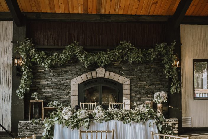 wedding sweetheart table at Canyon Ski resort in red deer alberta with fresh eucalyptus garland on mantle and along the front of the head table