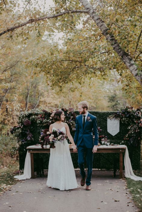 Bride and Groom in front of harvest table in the fall at Mckenzie trails with florals in burgundy and blush