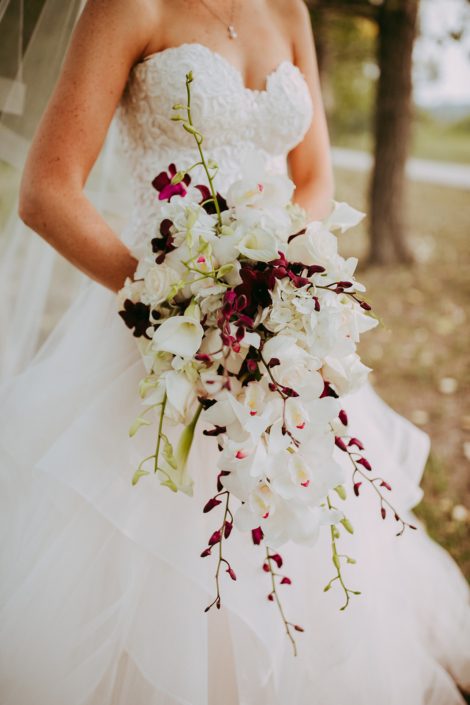 Close up photo of Cascade bridal bouquet designed with white cymbidium orchids and white and burgundy dendrobium orchids and white calla lilies