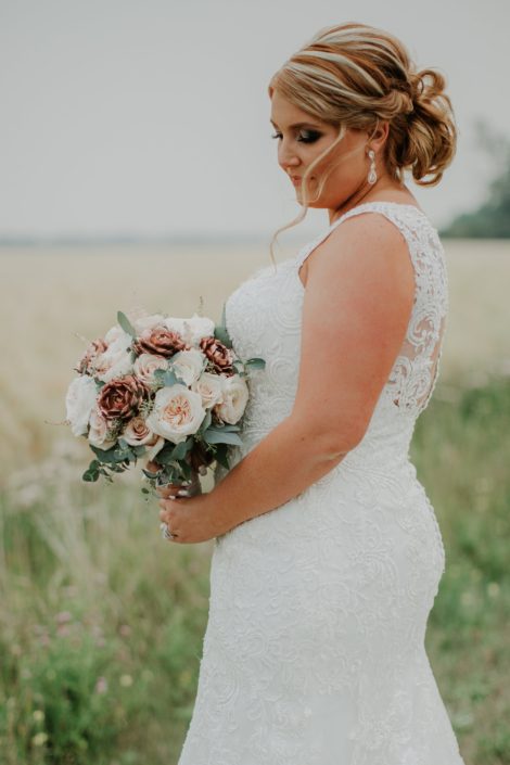 bride with blonde updo and wedding dress holding a bridal bouquet designed with rose gold succulents, ivory garden roses and blush spray roses and eucalyptus
