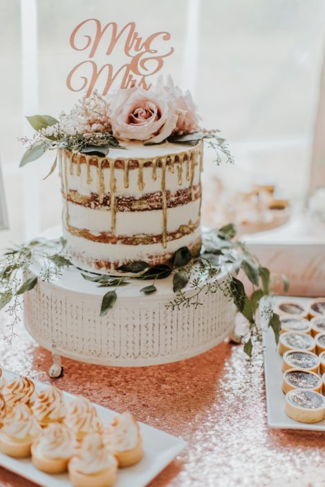 naked cake with gold drip and eucalyptus and blush rose topper and mr and mrs topper on rose gold sequin tablecloth