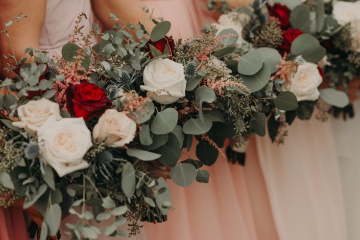 bouquet close up of blush wedding with red roses quicksand roses navy eryngium and pink astilbe and white o'hara garden roses and mixed eucalyptus