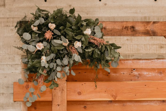 rustic wedding arch way with floral corner accent made with blush roses and pink astilbe and silver dollar eucalyptus