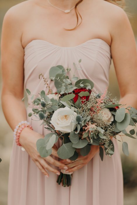 Blush bridesmaid dress with bouquet of white o'hara garden roses quicksand roses and red roses and eryngium and pink astilbe and mixed eucalyptus