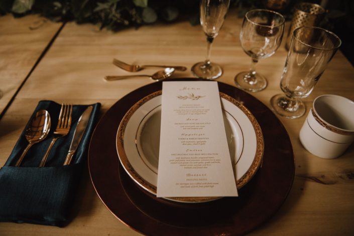 Elegant table setting with teal napkin and menu card on a gold charger