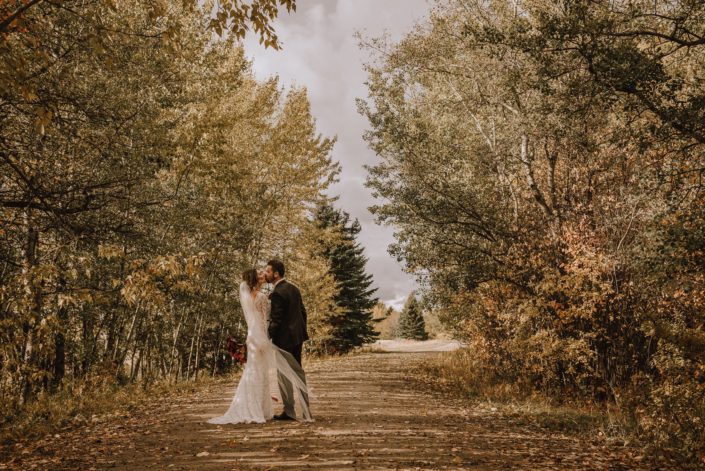 Bride and groom kiss on the path at Canyon Ski Resort in the autumn