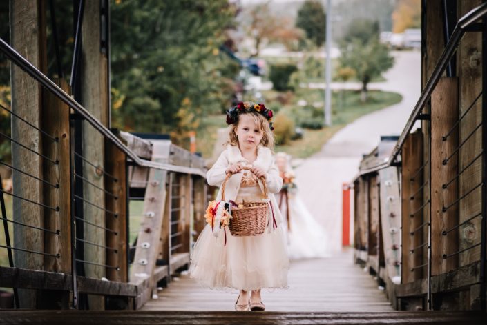 Flowergirl wearing a flowercrown of chrysanthemum, spray roses and eryngium and carrying a basket of autumn colored rose petals