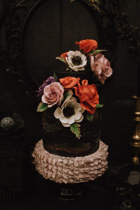 alternative wedding cake with sugar anemone red roses and mauve roses on black cake