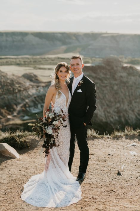 bride and groom at a styled photoshoot in the drumheller badlands with a lace dress and a loose organic bridal bouquet