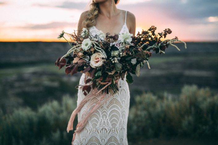 bride holding bridal bouquet designed with roses, amaranthus, scabiosa and burgundy greenery