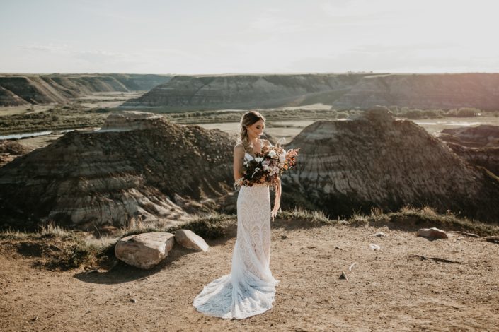 bride in the drumheller badlands in a lace dress holding an organic boho styled bridal bouquet