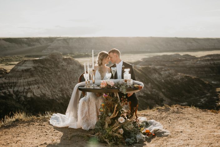 bride and groom at sweetheart table overlooking the drumheller badlands with driftwood floral accents