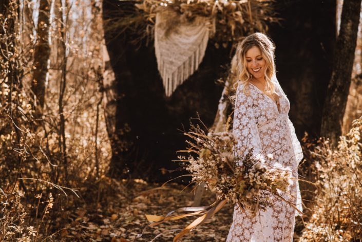 Blonde boho bride in crochet dress in the fall in the woods with dried pampas grass back drop with crochet and bouquet of foraged dried flowers