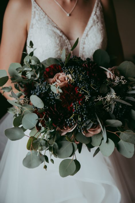 bridal bouquet close up with red roses burgundy dahlias amnesia roses navy viburnum berries and mixed eucalyptus