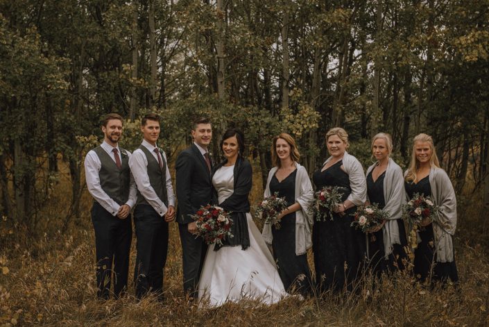 bridal party photo with bridesmaids in grey shawls and bridal bouquets designed with burgundy and navy flowers