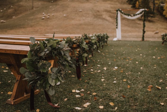 Ceremony decor at Canyon skir resort with eucalyptus hoop aisle markers and mixed greenery garland draped on the archway