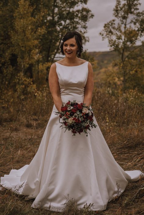 bride in Kleinfelds ivory wedding dress holding a bridal bouquet of burgundy and navy flowers with eucalyptus greenery
