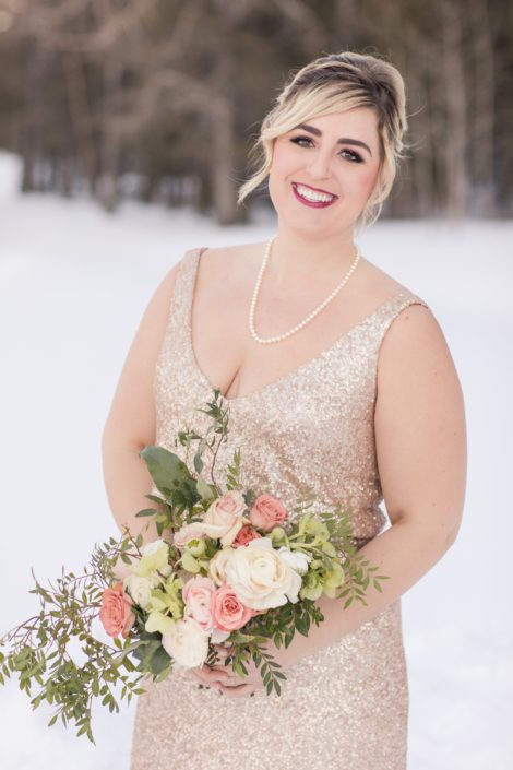 Winter Bridesmaid in blush sequin dress with oblong bridesmaid bouquet in ivory and peach roses