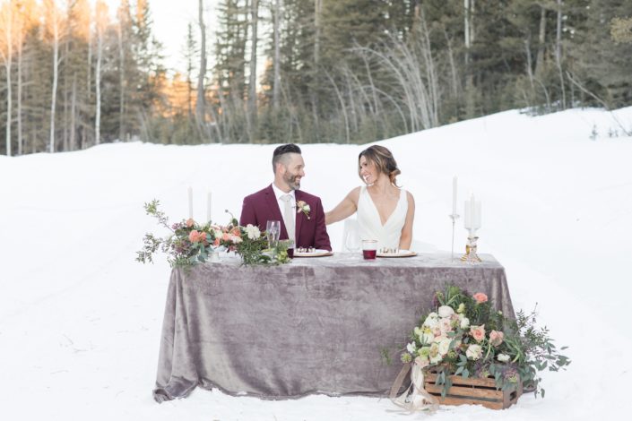 Winter wedding with bride and groom in burgundy suit Flowers in white, ivory and peach