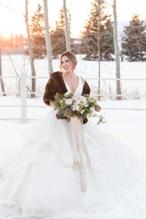 Winter bride with brown fur shawl and bridal bouquet with blush ranunculus and ivory roses