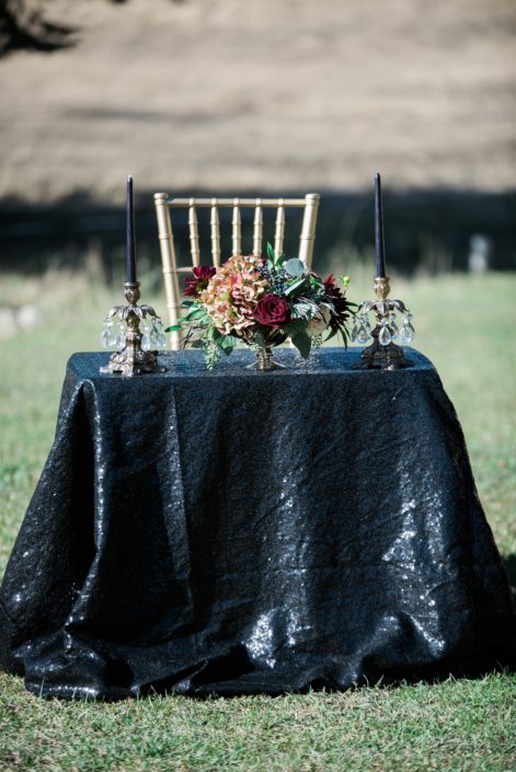 wedding signing table at Canyon Ski Resort with black sequin tablecloth and black candles and a compote style centerpiece designed with burgundy roses and hydrangea