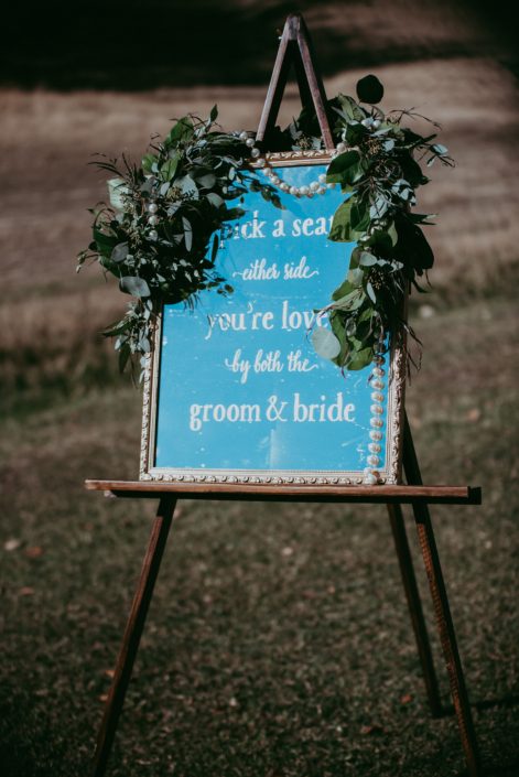 Wedding welcome seating sign accented by pearls and a mixed eucalyptus greenery garland