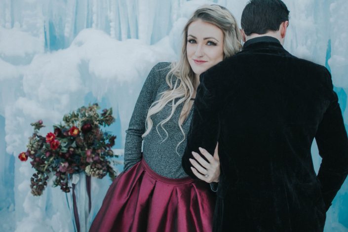 engagement photoshoot at the ice castles in edmonton with a burgundy taffetta dress and burgundy bridal bouquet
