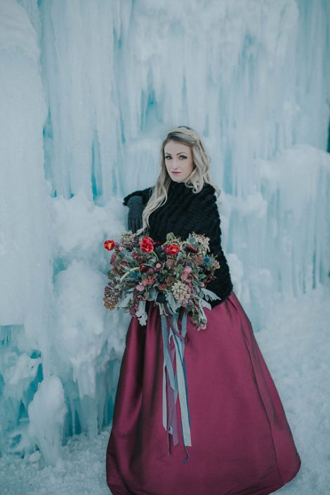 Engagement photo at the ice castles with bride bouquet of tulip frittilaria and skimmia in burgundy and red with trailing silk ribbons in grey