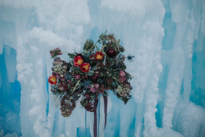 A loose and natural bridal bouquet at the edmonton ice castles de signed with burgundy frittilaria, burgundy ranunculus, red tulips and burgundy helleborus