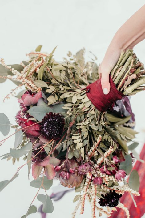 bridal bouquet designed with plum scabiosa, pieris japonica and burgundy helleborus tied with burgundy silk ribbon