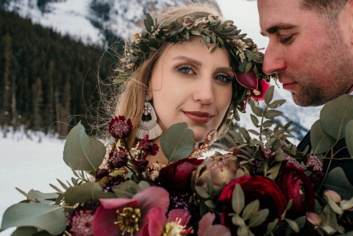 close up of bride with flower crown and burgundy ranunculus bridal bouquet