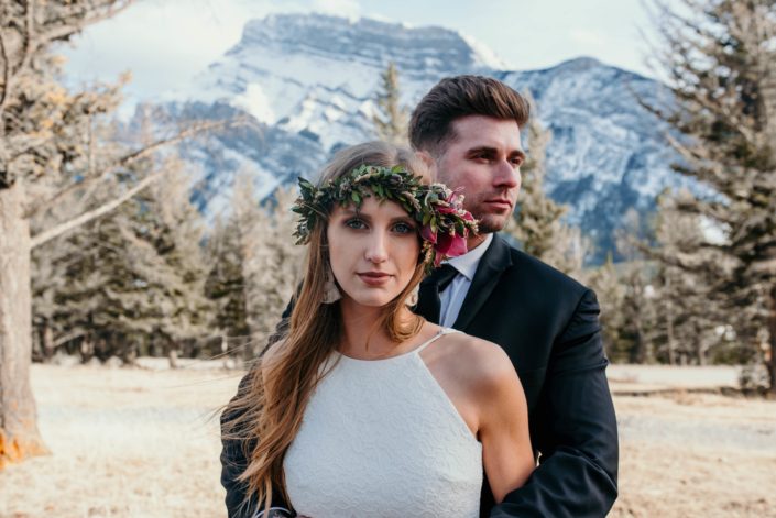 Bride wearing burgundy floral crown with groom in mountains