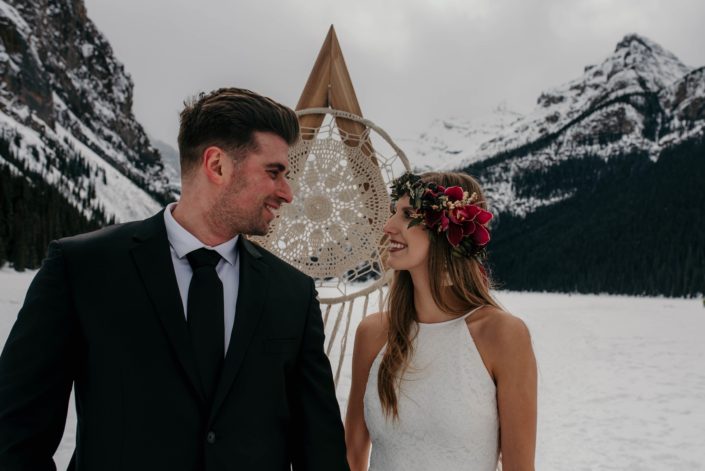 bride and groom at lake louise with boho backdrop and flowercrown with burgundy cymbidium orchids