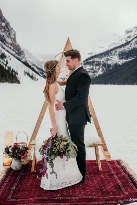 lake louise elopment photoshoot with burgundy rug and triangle archway