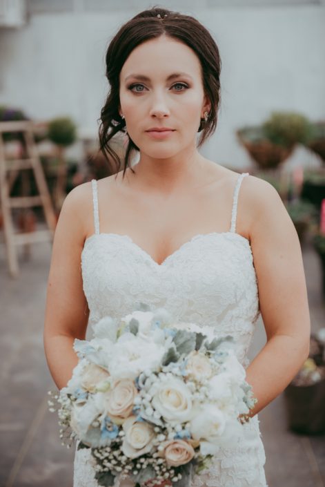 bride holding a bridal bouquet of ivory rose, white peony and pale blue delphinium