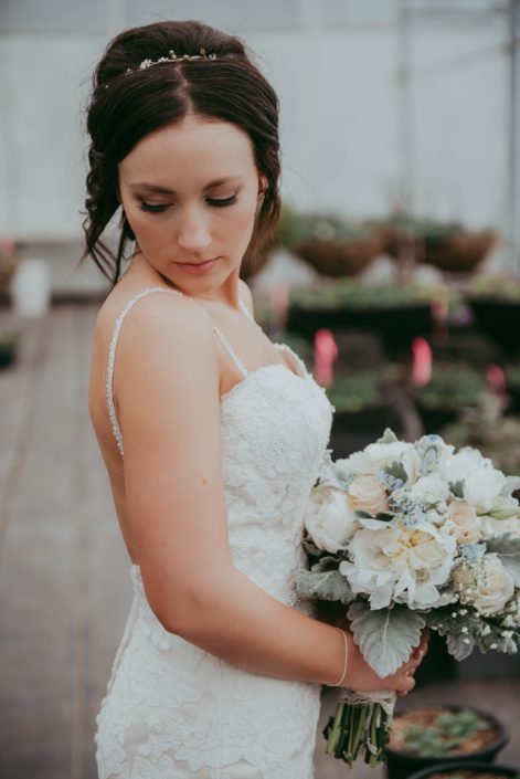 bride holding a bouquet of white peony, ivory rose and dusty miller