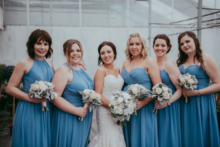 bride and bridesmaids in sky blue dresses with ivory and cream roses and grey dusty miller greenery