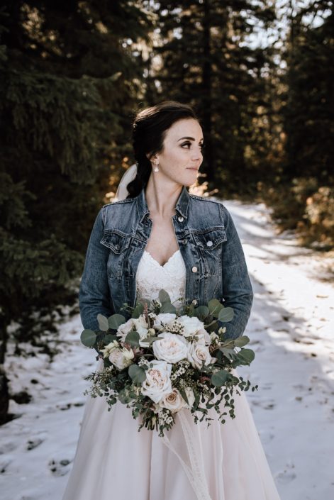 Bride in jean jacket with bouquet of playa blanca white roses and eucalyptus